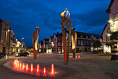 'Sculptures illuminated at dusk along a city street; Hertfordshire, England'