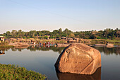 'A group of people bathing and cleaning clothes in the river; Hampi, Karnataka, India'