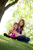 Mother And Daughter Sitting In A Park