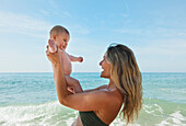 'A Mother Plays With Her Baby At The Beach; Banalmadena Costa, Malaga, Andalusia, Spain'