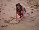 Girl Drawing Heart In The Sand