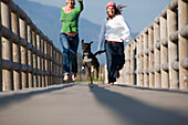 Two Women Running With A Dog