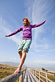Young Woman Balancing Barefoot On Wooden Structure