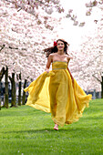 Woman In Yellow Dress Running Among Flowering Trees