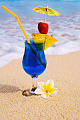 A Blue Hawaii Tropical Cocktail On The Beach, Wave Washing On The Sand.