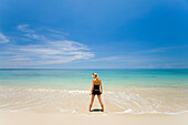 Eine Touristin steht im flachen, klaren Wasser einer tropischen Insel; Koh Lanta, Thailand