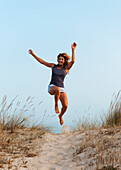 'A Young Woman Running And Leaping Down A Sandy Path; Tarifa, Cadiz, Andalusia, Spain'