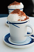 'A hot beverage served in a cup and saucer with foam and cinnamon;Zurich switzerland'