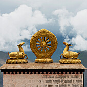 'Gold religious symbols on top of a wall ledge with clouds in the background;Lhasa xizang china'