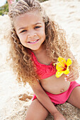 'Portrait of a girl on the beach holding a hibiscus flower;Waikiki oahu hawaii united states of america'