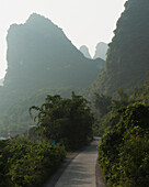'A path going through a landscaped area with mountain peaks and fog;Yangshuo guangxi china'