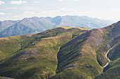 'Close up of rolling mountain hillside with mountain range in the background; Yukon, Canada'