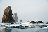 'Waves break around the stone needles; Cannon Beach, Oregon, United States of America'