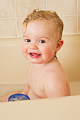 'A baby girl playing in the bathtub; Alberta, Canada'