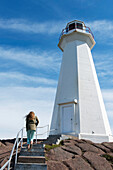 'A young woman climbs steps towards the Cape Spear Lighthouse; St. John's, Newfoundland and Labrador, Canada'