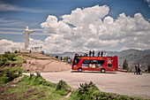 roter Touristenbus hält bei Aussichtsplatform zur Christus Statue mit Blick auf Anden, Cusco, Peru, Süd Amerika