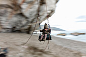 Boy (2 years) swinging at beach, Taormina, Messina, Sicily, Italy