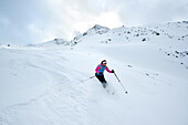 Female back-country skier downhill skiing from Piz Laschadurella, Sesvenna Alps, Engadin, Graubuenden, Switzerland