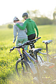 Two cyclists with E-bikes resting in a flower meadow, Munsing, Upper Bavaria, Germany