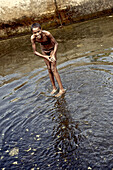 Boy standing in a stone basin with water, Praia, Santiago, Cape Verde