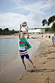 Junge mit Ball am Strand vor Hostal Spa Empuries, Platja del Portitxol, Girona, Costa Brava, Spanien