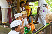 Balinese kids playing with German young boy, 3 years old, traditional clothes at temple ceremony, Balinese religion, stroller, intercultural contact, meeting local people, locals, family travel in Asia, parental leave, German, European, MR, Munduk, Bali, 