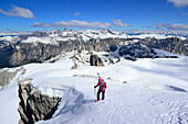 Female back-country skier ascending in Val Culea, Geisler Group in background, Sella Group, Dolomites, South Tyrol, Italy