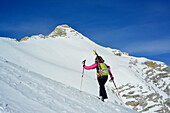 Female back-country skier ascending to Birkkarspitze, Oedkarspitze in backgrounds, Karwendel range, Tyrol, Austria