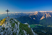 Wanderer sitzt am Gipfel des Kramerspitz, Wetterstein mit Wettersteinwand, Dreitorspitzen und Alpspitze im Hintergrund, Kramer, Ammergauer Alpen, Werdenfelser Land, Oberbayern, Bayern, Deutschland