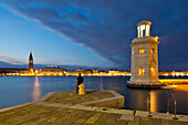 Kleiner Leuchtturm an der Einfahrt zur Marina der Isola di San Giorgo Maggiore Insel am San Marco Basin mit Blick auf Campanile di San Marco Turm und Dogenpalast am Markusplatz in der Dämmerung, Venedig, Venetien, Italien, Europa