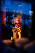 Smiling young woman looking through a window