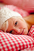 Young woman wearing a cap lying in bed