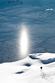 Skifahrer fährt ab, Lichtsäule im Hintergrund, St. Anton am Arlberg, Tirol, Österreich