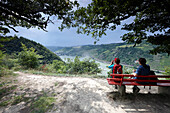 Hikers resting on a bench at view point Lennig, Bornich, Rhineland-Palatinate, Germany