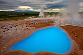 In backgroung the geyser Strukkur a moment before its eruption. Iceland.