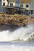 Surfer doing a big frontside air in a wintersuit in Maine