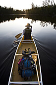 Sue Williams paddles her canoe out towards the sun in the still Boundary Waters of Minnesota on August 19, 2007.
