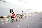 A smiling man and woman ride their bikes through a street in Portland, ME.