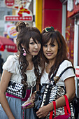 Shanghai, China - September 3, 2009: Two young Chinese women outside a row of fast food stores in downtown Shanghai.