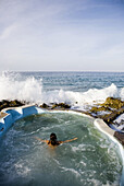 JAMAICA. A woman enjoys a small oceanside pool at a local, organic spa resort.