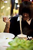 A teenage girl eats noodles at a hot pot restaurant, Taipei, Taiwan, November 8, 2010.
