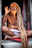 A Hindu priest, a sadhu and esthetic, with body paint poses in a Kathmandu, Nepal temple.