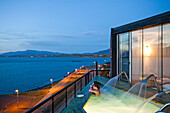 PUERTO NATALES, PATAGONIA, CHILE. A couple sits in an empty hot tub overlooking the waters surrounding Puerto Natales.