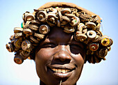 Woman from the Bumi tribe wearing hat made out of recycled bottle lids. Omerate,Omo Valley,Ethiopia,2010