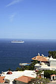 A large crusie ship sails past the exclusive multi-million dollar luxury villas that cling to the steep desert mountainsides in the Pedregal Hills overlooking the Pacific Ocean in Cabo San Lucas in Baja, Mexico. Photo by Harrison Shull/Aurora