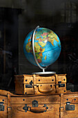 A globe on antique leather suitcases in a display window at a shop in Copenhagen, Denmark.
