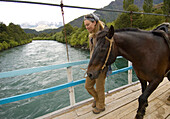 Anastacia Kampe leads her horse across a wooden bridge while on a horse trekking adventure in Futaleufu, Chile