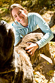 Tina Sommer scratching, loving and playing with  her dog Roxy while taking a break from trail running the trails near Santa Fe, New Mexico in the cool fall season.
