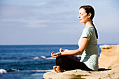 Eine Frau meditiert am Strand. releasecode: 20071030-LauraSparaco