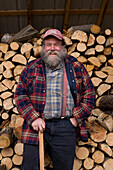 Man with axe and large pile of cut wood stockpiled for upcoming winter season - Juan de Santa Ana.
